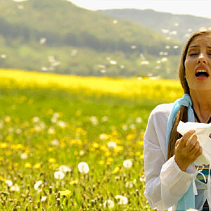 Woman sneezing with tissue in meadow