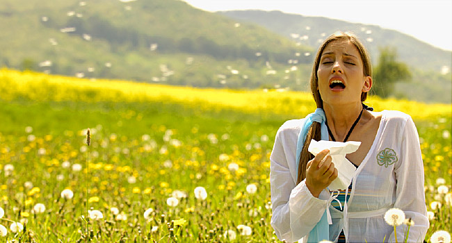 Woman sneezing with tissue in meadow